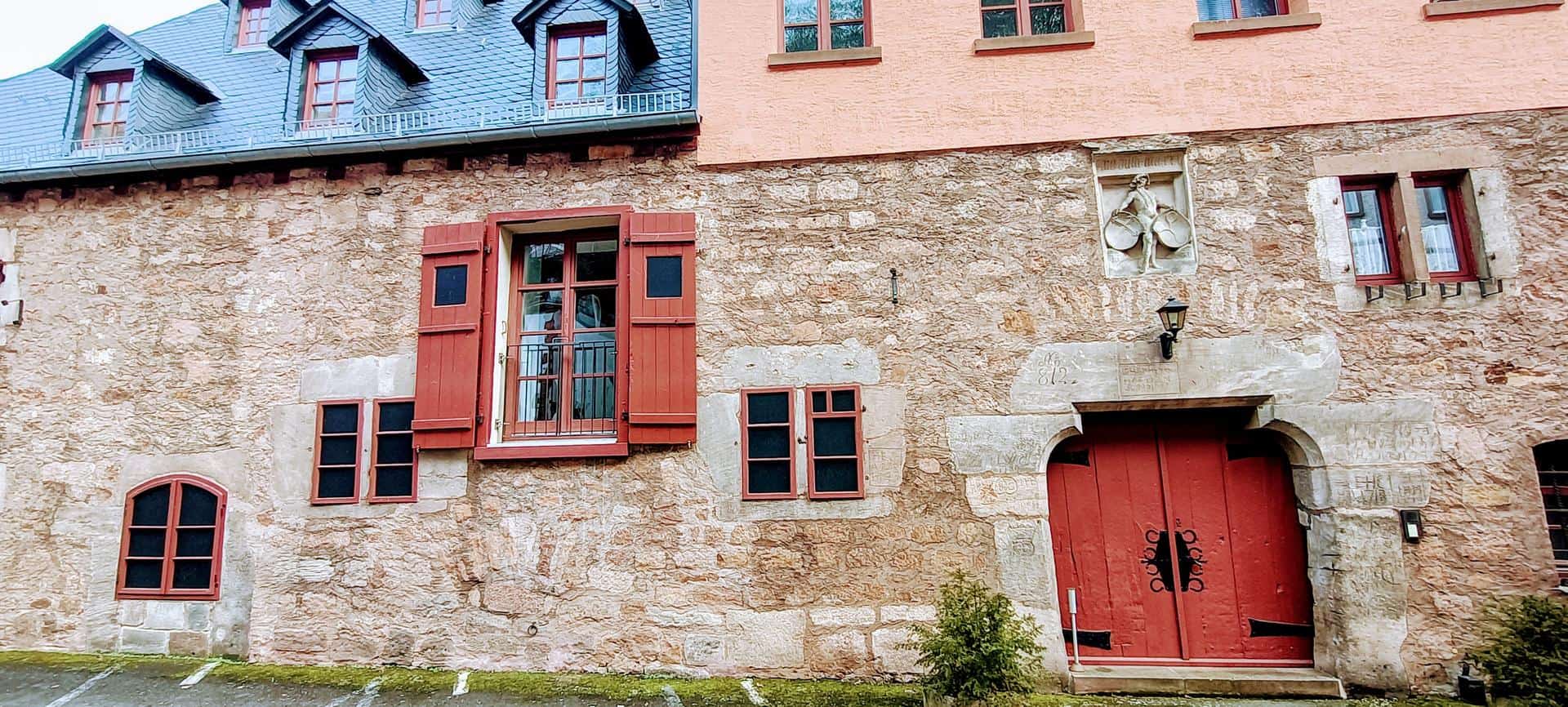 Historisches Gebäude in Marburg mit roten Fensterläden und Tür.
