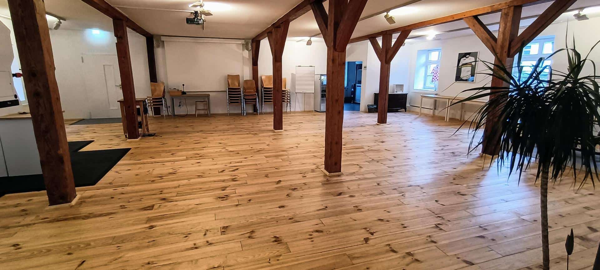 Großer, offener Raum mit Holzfußboden und Holzbalken, ideal für Fahrradkurse in Marburg.