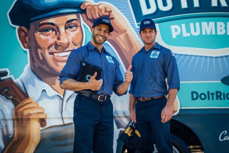 Two plumbers in uniform stand in front of a company van with branded artwork—one holds a tablet and gives a thumbs up, while the other holds a cap and tool bag, ready to tackle any plumbing repair.