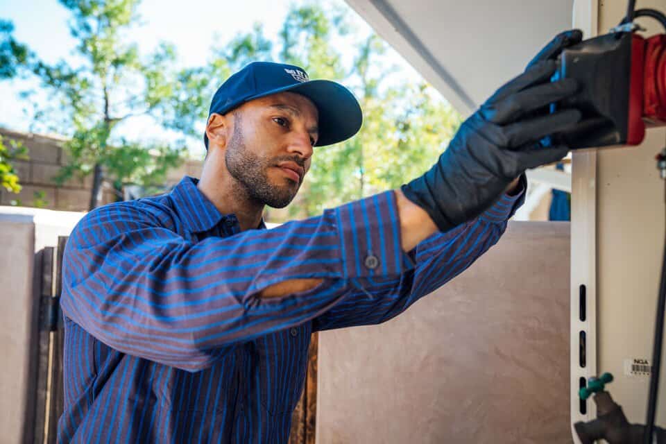 Aging tank water heater being inspected by a plumber in an Orange County home.