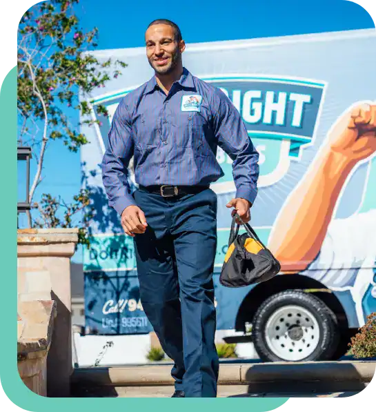 A man in business attire carries a small bag and walks outdoors in front of a branded truck with a logo and contact information.