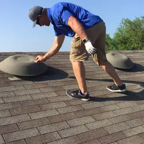 Roofer examining roof heat damage in San Antonio, checking asphalt shingles for wear