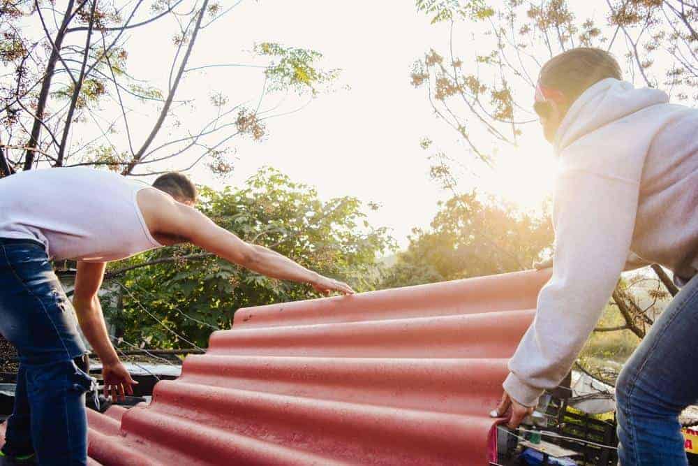 two men place a piece of metal roofing