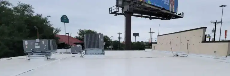 Flat commercial roof in San Antonio coated for waterproofing by Dolan Roofing & Construction, featuring HVAC units and smooth white coating