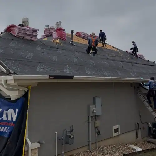 Roofers installing underlayment and staging shingles on a large residential roof, exemplifying professional service and roof financing near me by Dolan Roofing & Construction in San Antonio