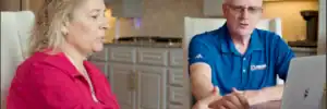 Homeowner sitting with Dolan Roofing & Construction representative discussing roof financing near me options at a kitchen table in San Antonio