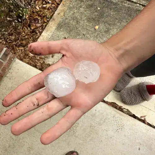 Large hailstones in hand illustrating the need for storm damage repair by Dolan Roofing & Construction