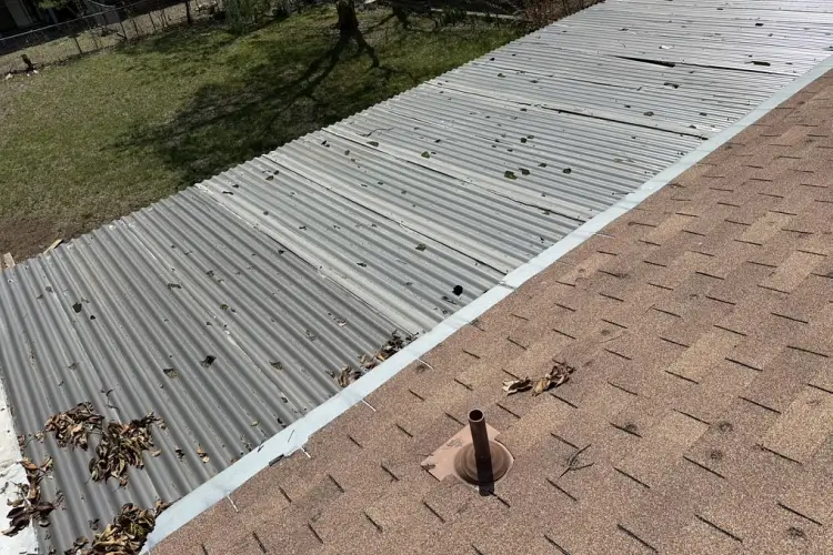 Metal roof with dents and brown shingles showing hail damage before repair San Antonio by Dolan Roofing & Construction