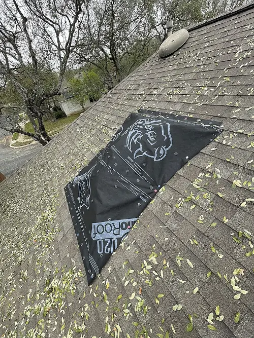 Black waterproof tarp covering damaged shingles as a temporary fix for hail damage repair San Antonio by Dolan Roofing & Construction