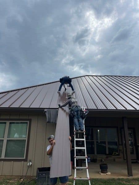 Workers installing durable metal roofing panels on a residential house by Dolan Roofing & Construction in San Antonio, TX.