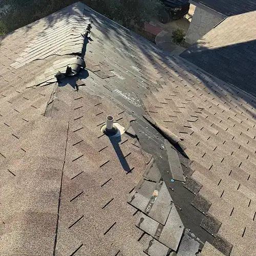 Broken ridge cap shingles as sign of roof wind damage by Dolan Roofing & Construction