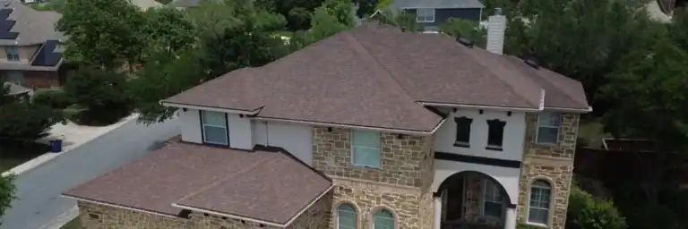 Freshly installed architectural shingle roof on a stone facade home, demonstrating added curb appeal and marketability tied to how much does a new roof add to home value by Dolan Roofing & Construction in San Antonio
