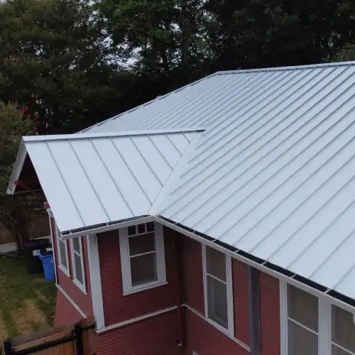 Modern white standing seam metal roof installed on red residential home, highlighting cost of metal roof San Antonio