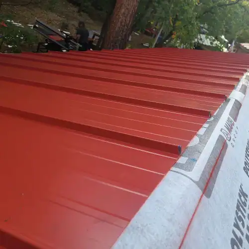 Red metal roof panels being installed on residential home, demonstrating cost of metal roof San Antonio