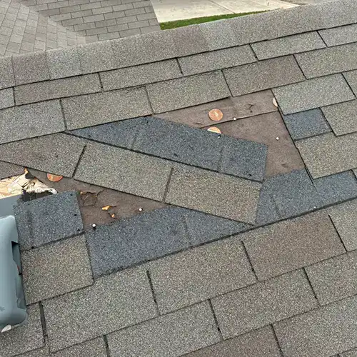 Roof missing several shingles—common sign of wind damage by Dolan Roofing & Construction