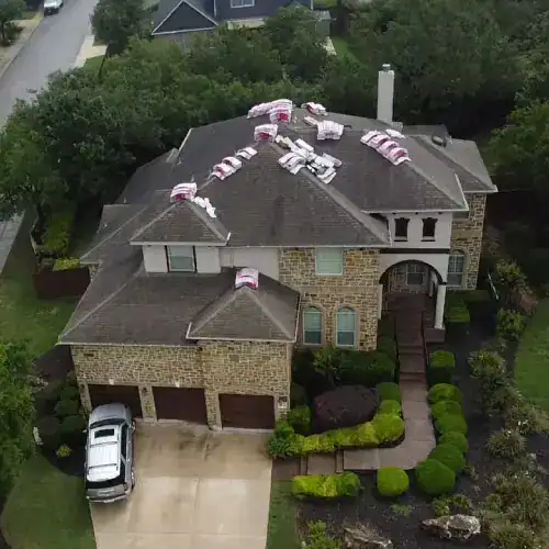 Aerial view of a San Antonio home staged with shingle bundles for roof replacement, illustrating factors in how much does a new roof add to home value by Dolan Roofing & Construction in San Antonio