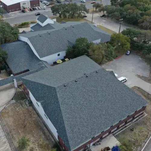 Expansive gray asphalt shingle roof on large brick church complex, highlighting professional church roof replacement San Antonio
