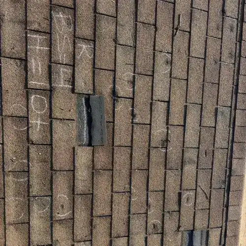 Close-up of asphalt shingles with chalk marks showing hail damage during a professional roof inspection in San Antonio