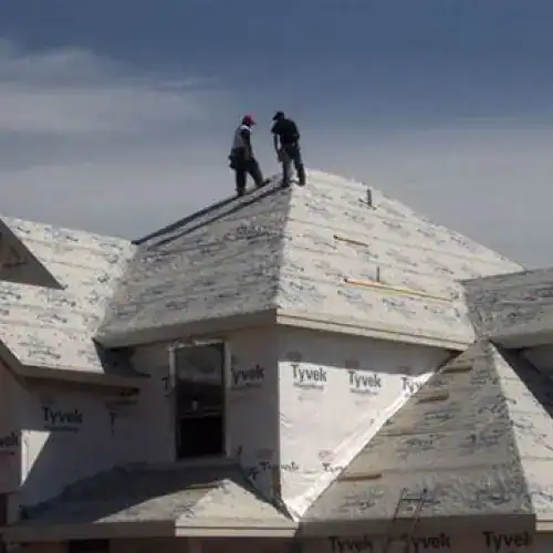 Two roofing contractors on a roof covered with underlayment, preparing for tile installation by Dolan Roofing & Construction in San Antonio 
