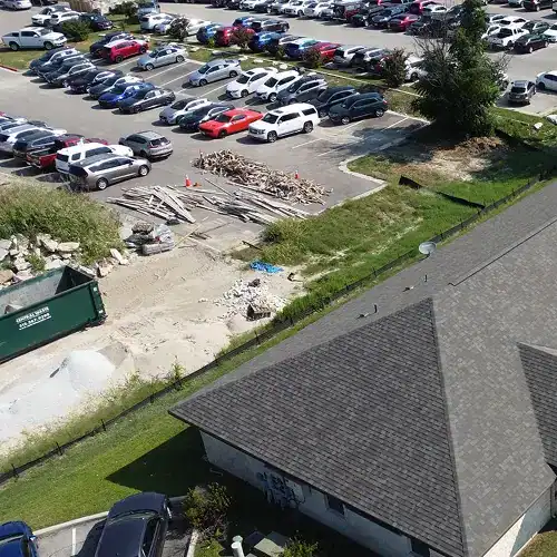 Cedar Park roof replacement adjacent to office parking lot, with new asphalt shingles and on-site construction materials by Dolan Roofing & Construction in San Antonio