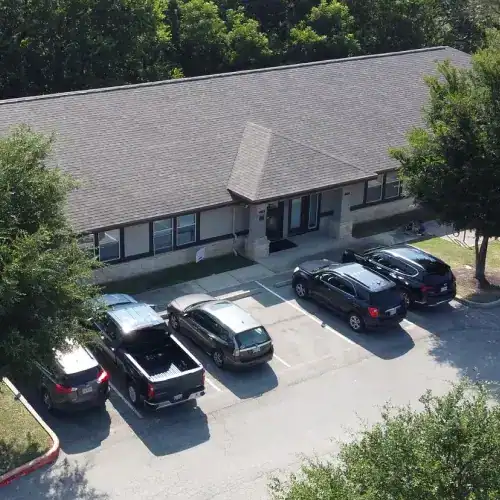 Cedar Park roof replacement shown on office building with new shingle roof and adjacent parking lot by Dolan Roofing & Construction in San Antonio