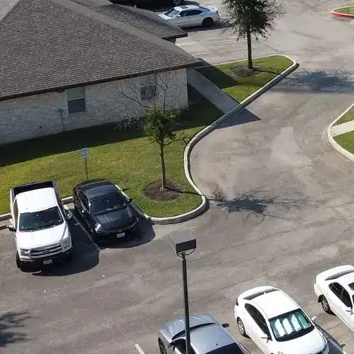 Cedar Park roof replacement with new shingle roofing on a stone commercial building and parking lot by Dolan Roofing & Construction in San Antonio