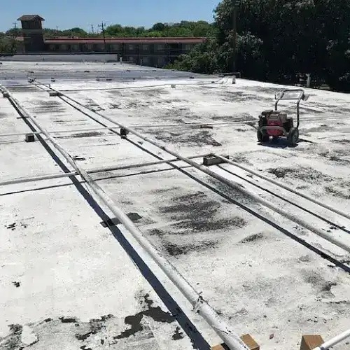 Flat commercial roof in San Antonio prepared for coating, showing weathered surface and equipment, by Dolan Roofing & Construction