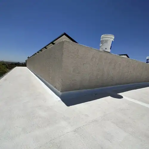 Freshly coated flat commercial roof with textured parapet wall and maintenance supplies, demonstrating commercial roof maintenance program San Antonio by Dolan Roofing & Construction in San Antonio, TX