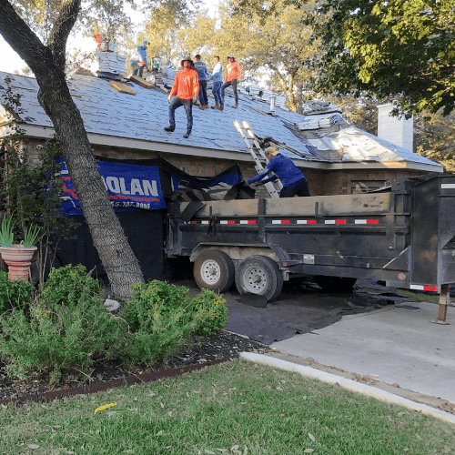 Roof replacement in progress by Helotes Roofing Contractor Dolan Roofing & Construction with crew removing old shingles at 13710 French Park in Helotes