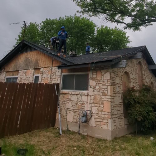 Roofing team replacing shingles on residential home during re-roof project by Dolan Roofing & Construction in Universal City