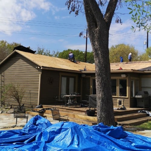 Roofing team reroofing residential home with deck exposed by Dolan Roofing & Construction in Alamo Heights