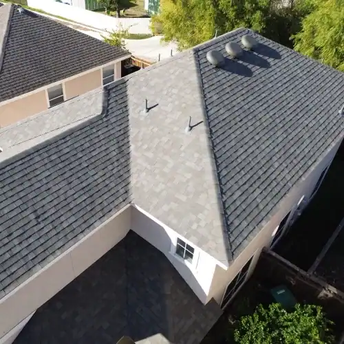 Aerial view of an asphalt shingle hip roof with ridge and box vents, showing coverage under a residential roofing warranty by Dolan Roofing & Construction in San Antonio
