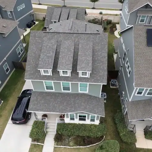 Top‑down view of a residential multi‑dormer asphalt shingle roof and gutters, reflecting residential roofing warranty coverage by Dolan Roofing & Construction in San Antonio