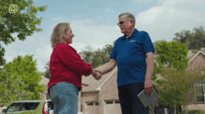 A customer and Dolan employee standing outside in front of houses, shaking hands to mark agreement or completion of a roofing service in San Antonio