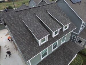 Aerial view of a residential roof with newly installed shingles and dormer windows, showing a finished roofing project in San Antonio
