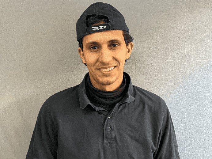 Lächelnder Mann in schwarzer Kleidung und Cap bei Drahtesel Fahrrad.