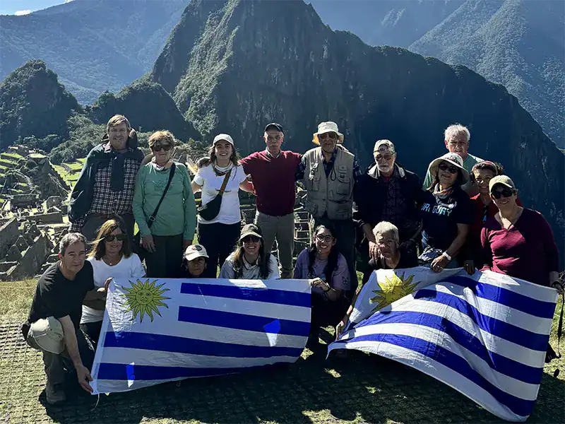 Group of hikers holding Uruguayan flags at Machu Picchu, Peru.