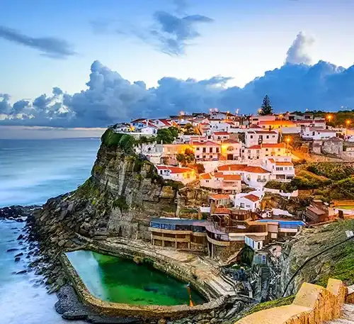 El pueblo costero en acantilados con casas blancas y vista al mar en la puesta de sol.