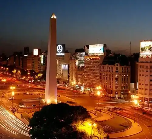 Torre de la Ciudad de México iluminada al atardecer con cielo oscuro.