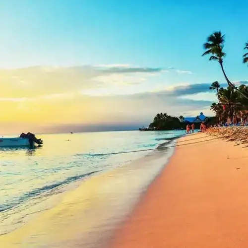 Playa tropical con palmeras y barco al atardecer en Uruguay.