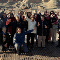 Enjoying a group outing outdoors on a wooden deck with scenic rocky background and clear skies.