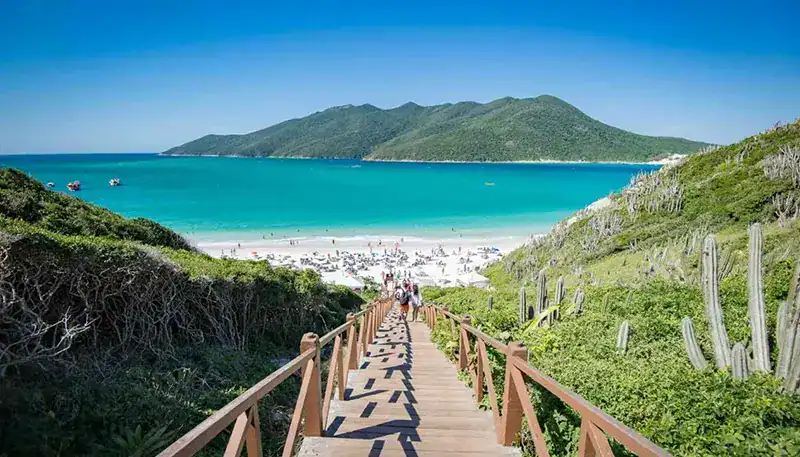 Vista de playa con escaleras y montañas en el fondo, paisaje costero en Uruguay.