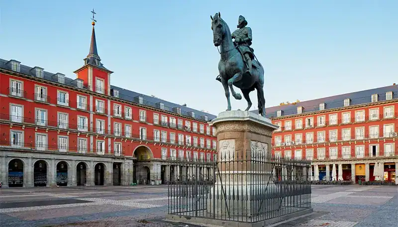Estatua ecuestre en una plaza con edificios históricos y cielo despejado.