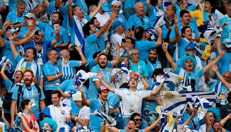 Apuesta de fútbol con hinchas celebrando con banderas y camisetas en el estadio.