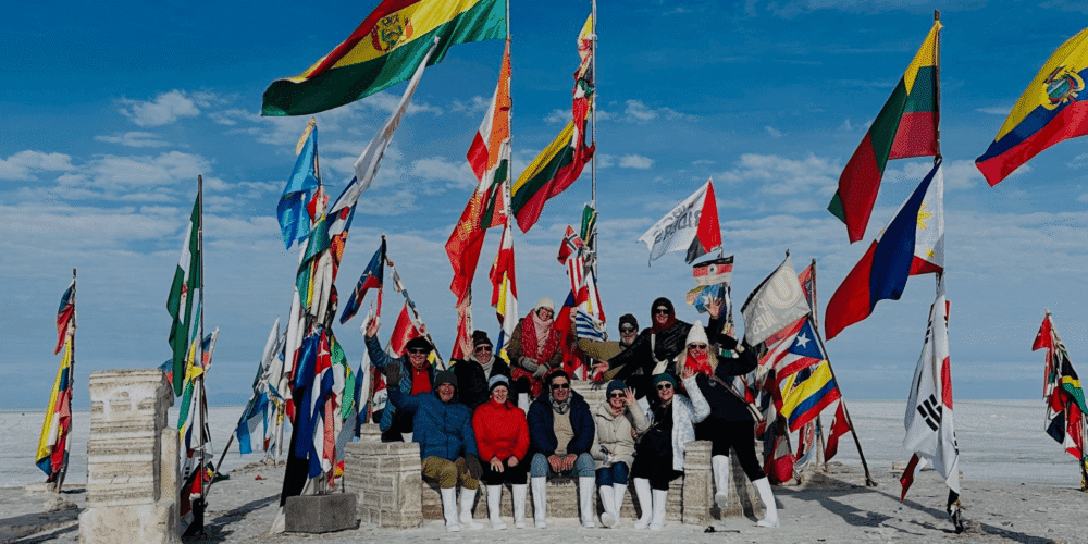Viento en la playa con banderas de diferentes países y grupo de personas disfrutando del paisaje.