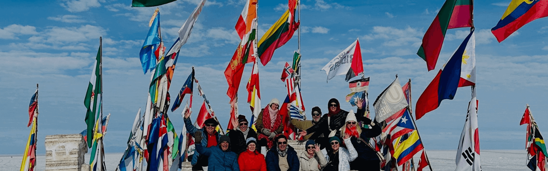 Viento en la playa con banderas de diferentes países y grupo de personas disfrutando del paisaje.