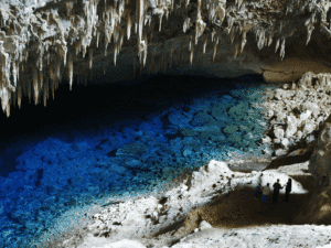 Cueva con estalactitas y agua cristalina en un entorno natural.