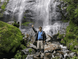 Cascada en un entorno natural con un hombre disfrutando de la naturaleza.