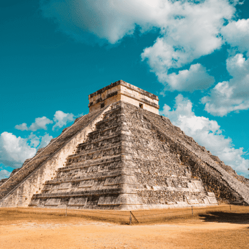 Ancient Mayan pyramid at Chichen Itza, Mexico, under a bright blue sky.
