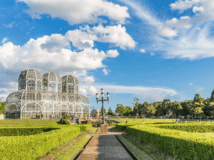 Jardín botánico con invernaderos de vidrio y estructura arquitectónica en un día soleado.